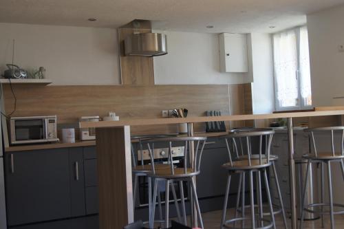 une cuisine avec un comptoir et des tabourets de bar dans l'établissement APPARTEMENT PROCHE BORD DE MER, à Plougasnou