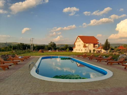 a swimming pool with benches and a house in the background at Pensiunea Agroturistica Green Odoba in Sătuc