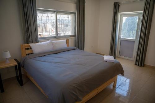 a bed in a bedroom with two windows at Dali House in Amman