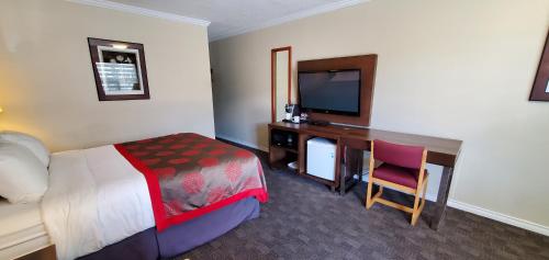 a hotel room with a bed and a desk with a television at Grand Forks Inn in Grand Forks