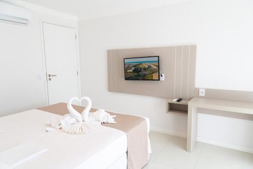 biały pokój z łóżkiem i telewizorem w obiekcie Golf Ville Resorts Suites w mieście Aquiraz