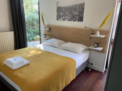 a bedroom with a bed with a yellow blanket and a window at BenB Het Posthuis in Nispen