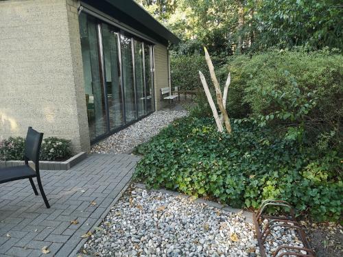 a patio with a chair next to a building at BenB Het Posthuis in Nispen
