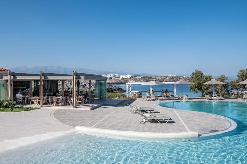 una piscina con mesas, sillas y agua en Kavos Hotel & Suites, en Stavros