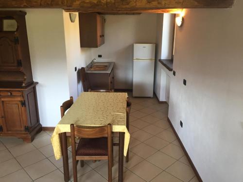 a kitchen with a table and chairs and a refrigerator at Agriturismo Il Balcone sulla Valle in Bedero Valcuvia