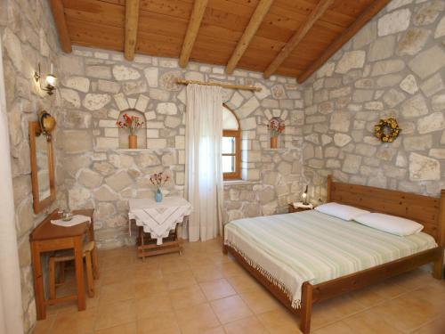 1 dormitorio con cama y pared de piedra en Gerolakos Country Houses, en Stavromenos