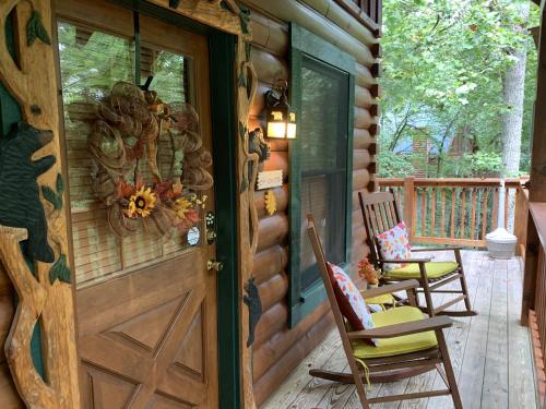 a wooden door to a cabin with chairs on a porch at Forest Fling Cabin in McCookville