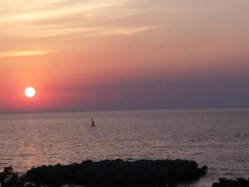 a sail boat in the ocean at sunset at Queen Apartments & Rooms in Dobra Voda