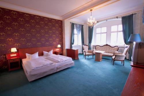 ein Schlafzimmer mit einem Bett, einem Sofa und Stühlen in der Unterkunft Schloss Beichlingen in Beichlingen