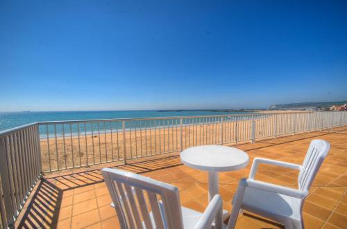 a balcony with a table and chairs and the beach at Apartamentos Playa Barbate in Barbate