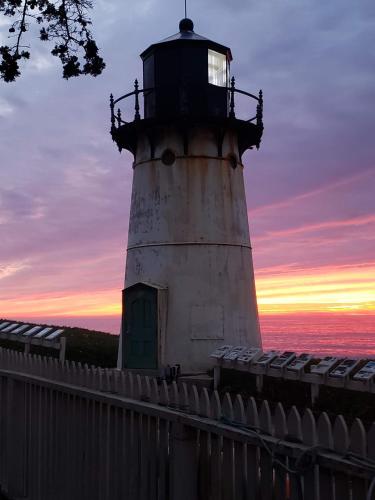 a lighthouse with a fence in front of a sunset at HI Point Montara Lighthouse in Montara