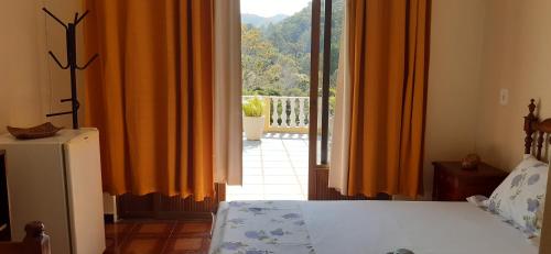 a bedroom with a bed and an open door to a balcony at Morada Recanto das Flores in Miguel Pereira