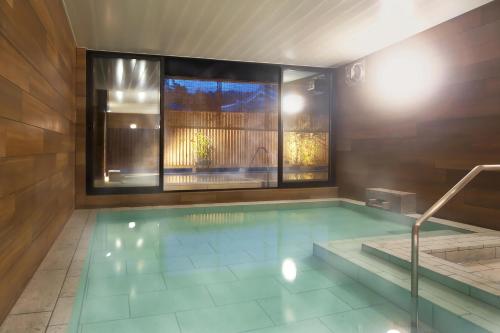 a large swimming pool with a large window and a tub at Kusatsu Onsen Kusatsu Hotel1913 in Kusatsu