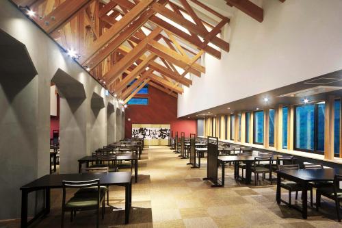 a dining room with tables and chairs and wooden ceilings at Kusatsu Onsen Kusatsu Hotel1913 in Kusatsu