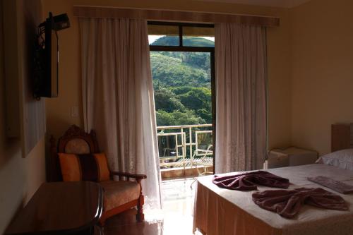 a bedroom with a bed and a window with a view at Morada Recanto das Flores in Miguel Pereira