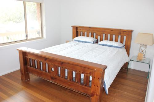 a wooden bed in a room with a window at Location @ Little Beach in Nelson Bay