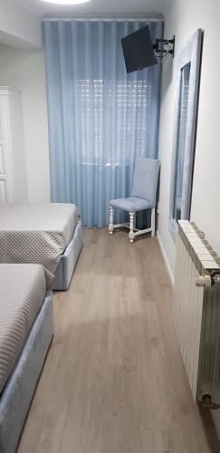 a room with two beds and a chair and a television at Residencial Solar da Estação in Barcelos