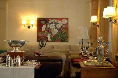 a living room with a couch and a painting of flowers at Belle Epoque Hotel Victoria & Apartments in Kandersteg