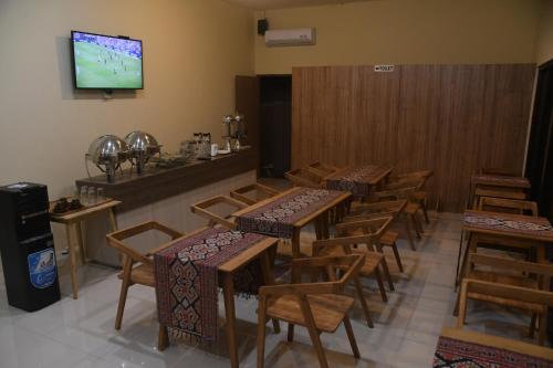 a restaurant with tables and chairs and a tv on the wall at Pasola in Tambolaka