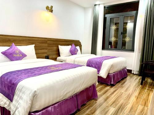 two beds in a hotel room with purple and white sheets at Golden Inn Hotel in Hue