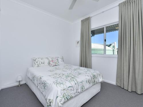 a white bedroom with a bed and a window at Kinloch Cottage renovated to new on Daisy Hill Vineyard in Pokolbin