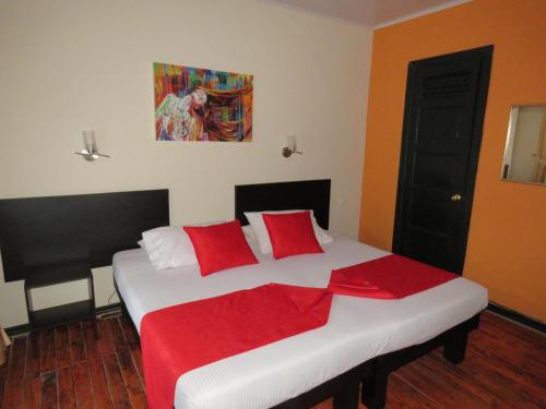 a bedroom with a large white bed with red pillows at Hotel La Herreria Colonial in Popayan