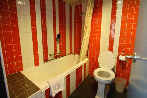 a bathroom with a toilet and a bath tub with red tiles at Baiyoke Boutique Hotel in Bangkok