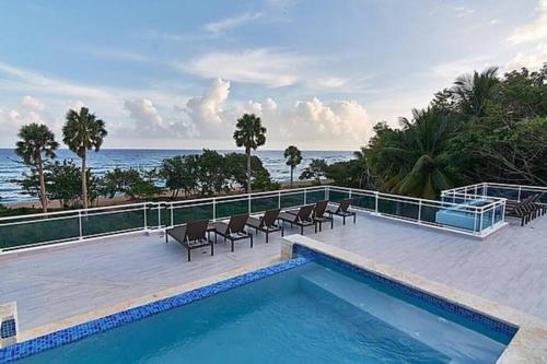 a swimming pool with chairs and the ocean in the background at Best ocean view Sosua-Cabarete in Sosúa