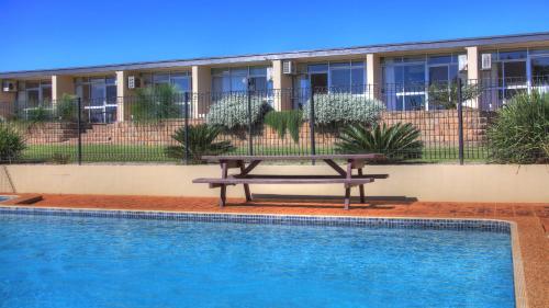 a picnic table by a swimming pool in front of a building at Atherton Apartments in Atherton