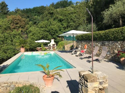a swimming pool with chairs and an umbrella at CASA DELLA LUCE private pool in Bagnone