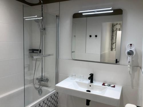 a bathroom with a sink and a shower and a mirror at Hôtel Moderna in Cherbourg en Cotentin