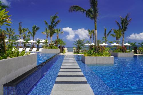 - une piscine dans un complexe avec des palmiers et des parasols dans l'établissement FUSAKI BEACH RESORT HOTEL & VILLAS, à Ishigaki