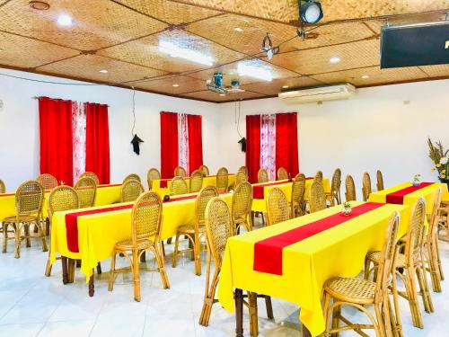 a room with yellow tables and chairs and red curtains at Dolce Vita Hotel in Puerto Princesa City