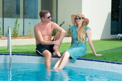 a man and a woman sitting in a swimming pool at First Central Hotel Suites in Dubai