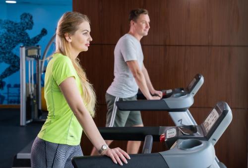 a man and woman running on a treadmill in a gym at First Central Hotel Suites in Dubai