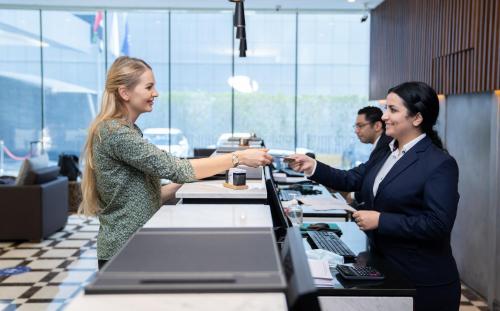 two women shaking hands at a desk in an office at First Central Hotel Suites in Dubai
