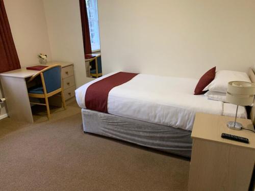 a hotel room with a bed and a desk at Hinsley Hall in Leeds