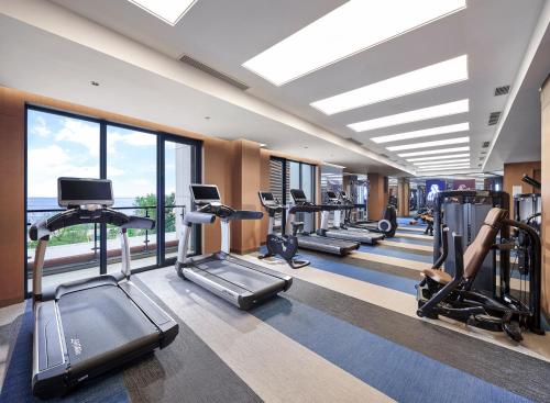 a gym with a row of treadmills and ellipticals at Hard Rock Hotel Dalian in Dalian