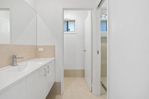 a white bathroom with a sink and a mirror at Location @ Little Beach in Nelson Bay