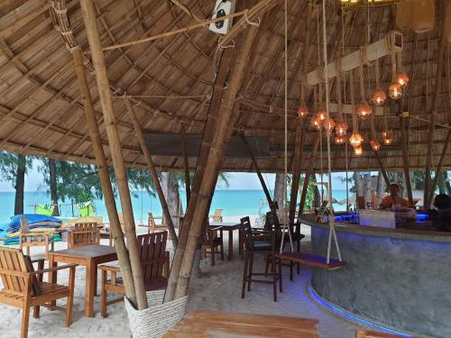 a restaurant with tables and chairs under a large umbrella at Long Beach Chalet - SHA Extra Plus in Ko Lanta