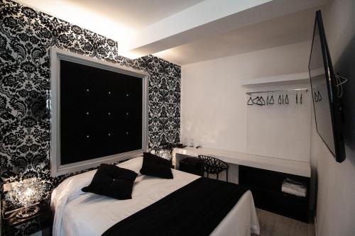 Hotel La Compagnia Del Viaggiatore في لاكويلا: غرفة نوم مع سرير وورق جدران أبيض وأسود