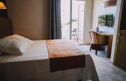 a bedroom with a bed and a desk and a balcony at Hotel Alba Seleqtta in Lloret de Mar