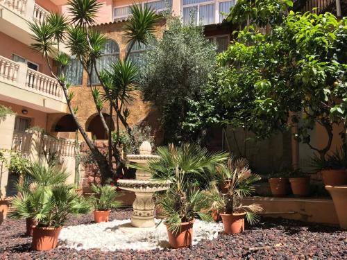 a garden with a fountain and plants in front of a building at Hotel Alba Seleqtta in Lloret de Mar