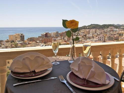 a table with plates and wine glasses on a balcony at Hotel Alba Seleqtta in Lloret de Mar