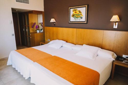 um quarto com uma grande cama branca e uma cabeceira em madeira em Hotel Alba Seleqtta em Lloret de Mar