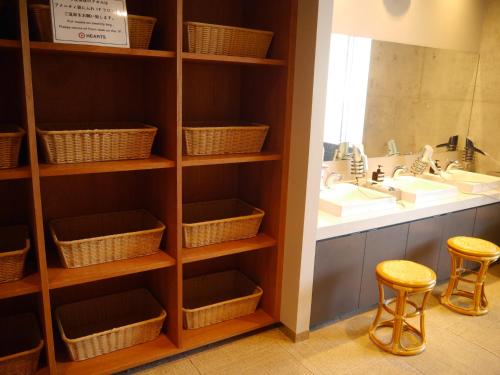 a bathroom with two stools and a sink and a shelf with baskets at HEARTS Capsule Hotel & Spa HAKATA in Fukuoka