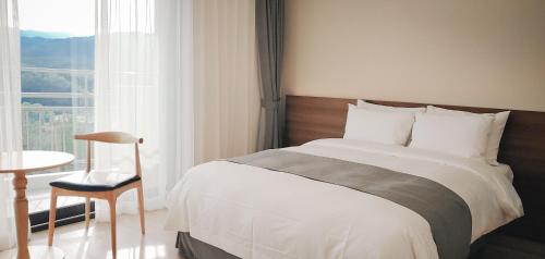 a bedroom with a bed and a chair and a window at The N Resort Hotel&Spa YangYang in Yangyang