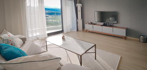 a living room with a glass coffee table and a television at The N Resort Hotel&Spa YangYang in Yangyang