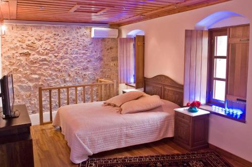 a bedroom with a bed and a stone wall at Ardamis in Monemvasia