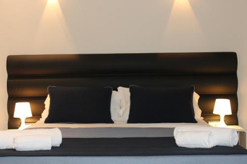 a bed with a black headboard and two lamps at Little Rose Lodge in Rome